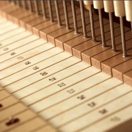 Close-up of piano hammers poised above strings inside a piano.