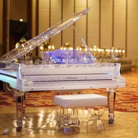 Elegant transparent grand piano with matching bench in a sophisticated setting.