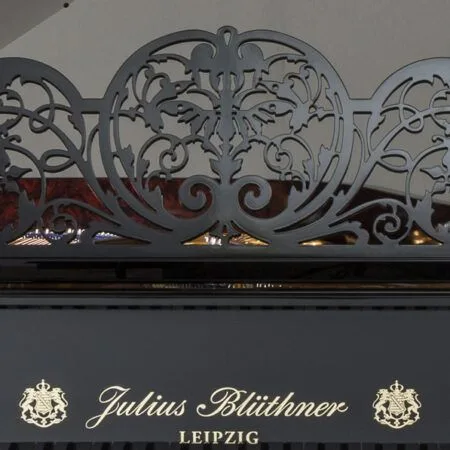 Vintage Julius Blüthner Leipzig piano with ornate metal music stand.