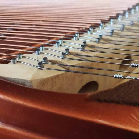 Close-up of piano strings and tuning pins inside a piano.