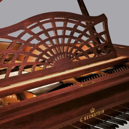 Elegant wooden piano with intricate music stand design and visible keys.