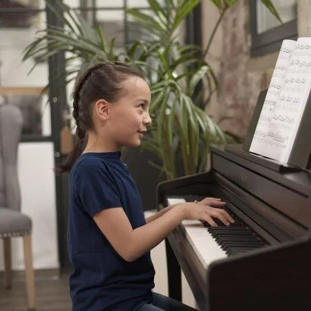 Young girl playing piano with sheet music in a cozy room.