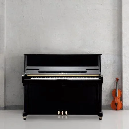 A black upright piano with a violin resting against the wall beside it.