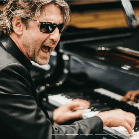 Man passionately playing piano with sunglasses on.