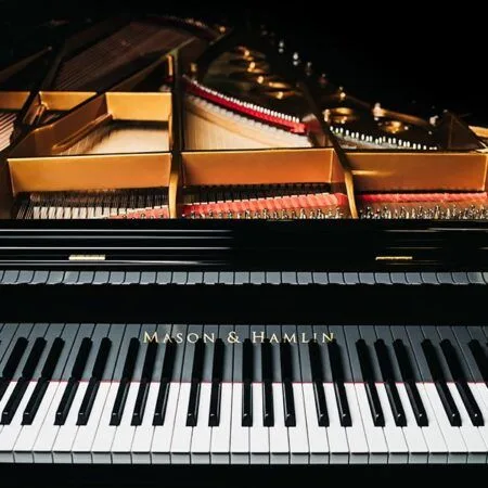 Close-up of a piano keyboard and strings inside a grand piano.