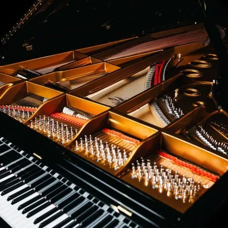 Close-up of a grand piano's strings and keyboard under warm lighting.