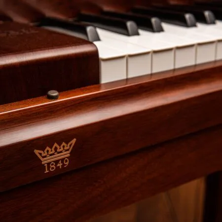 Close-up of a polished wooden piano with a crown emblem and the year 1849.