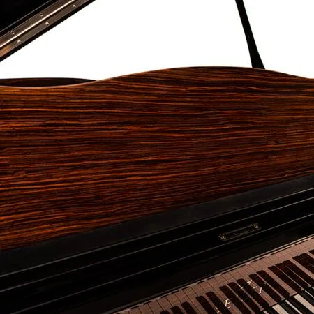 Close-up of a grand piano's wooden lid and keyboard keys.