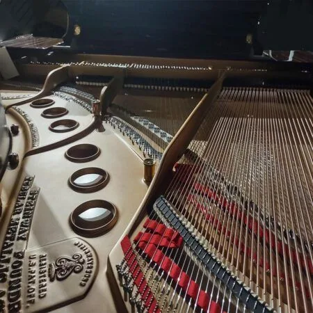 Close-up of a grand piano's strings and tuning pins inside the body.