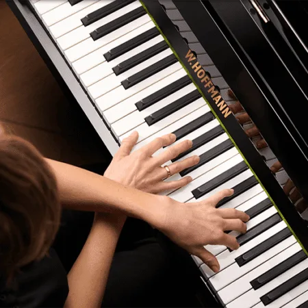 Hands playing a Steinway & Sons grand piano.