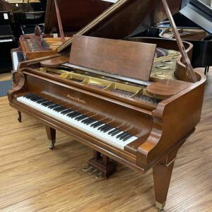 Antique wooden grand piano in a cozy room with wooden floors.