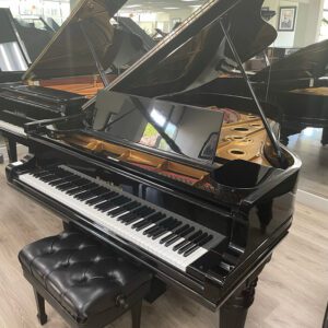 A glossy black grand piano with its lid open and a matching black bench.