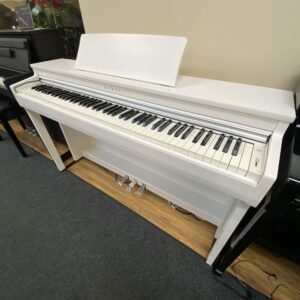 A sleek white piano in a room with a wooden floor and black carpet.