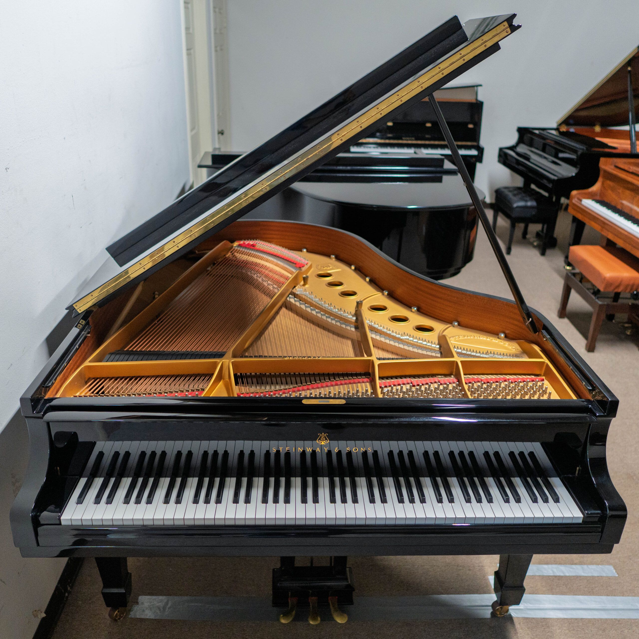 Open grand piano showing strings and keys in a music room.